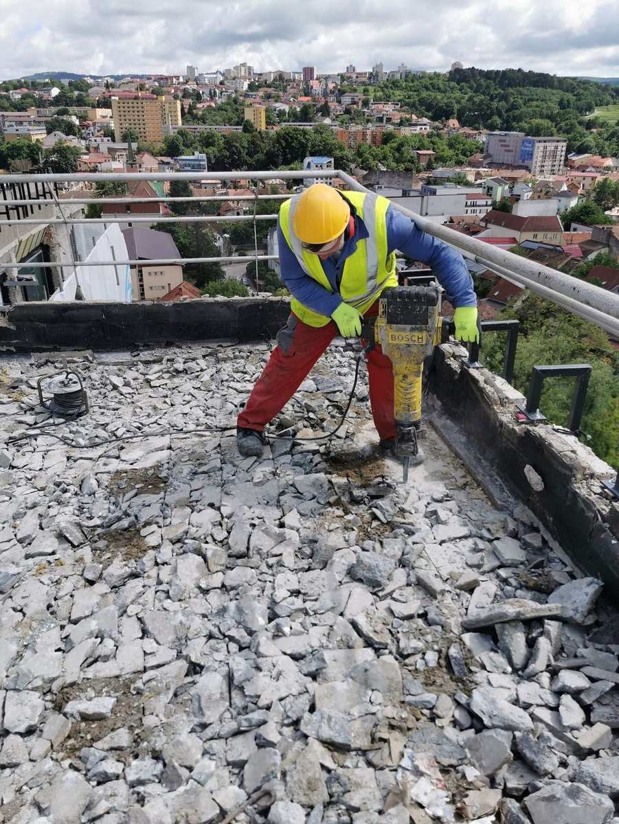 Operario con martillo demoledor Bosch levantando el pavimento de una cubierta plana en un edificio alto
